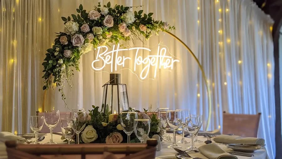 'Better Together' neon sign glowing at a wedding reception