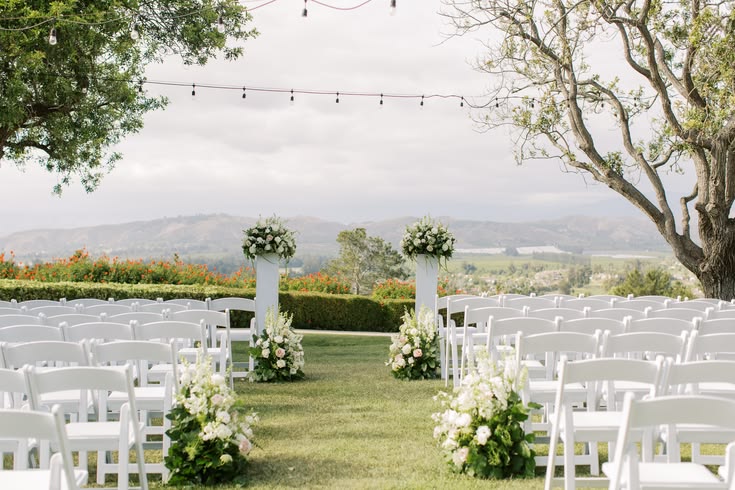 Ceremony chairs and floral arbour strung with festoon lighting at golden hour